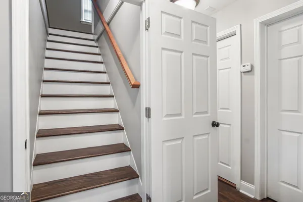 a view of staircase with wooden floor and white walls
