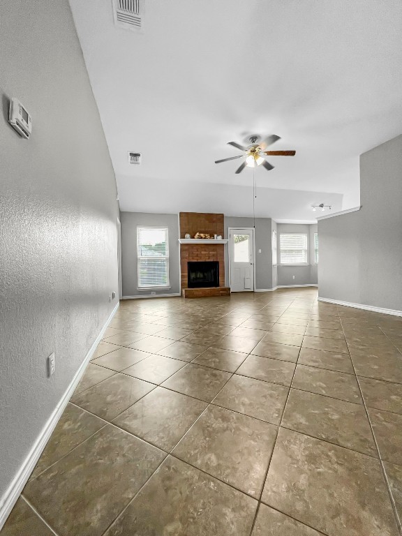 4701 High Pointe Drive Temple, TX 76502 - Photo 5 of 10 Unfurnished living room featuring a fireplace, a textured wall, tile patterned flooring, and a ceiling fan
