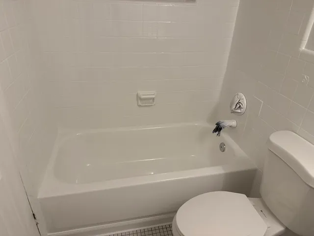 a white toilet and tub sitting next to a bathroom sink