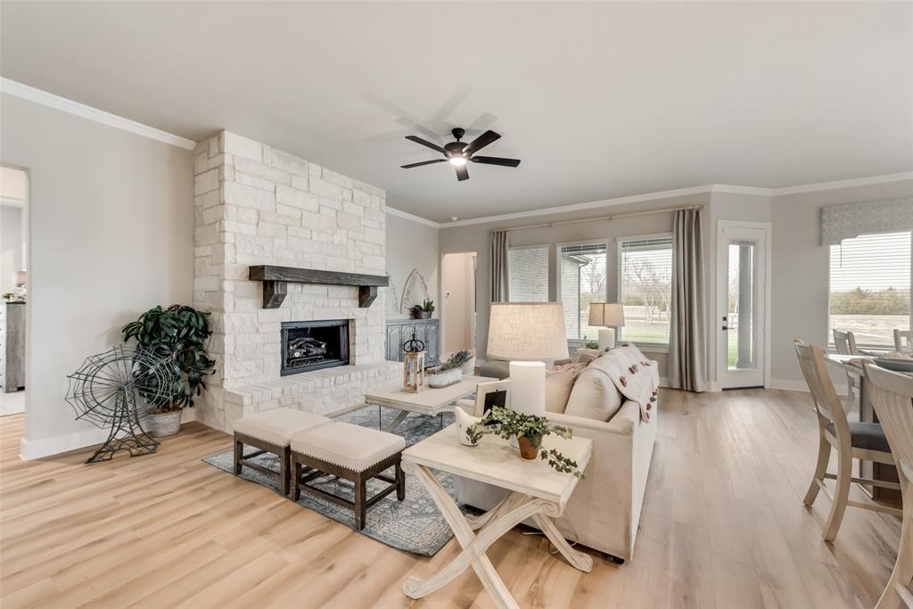 250 Brown Road Leonard, TX 75452 - Photo 9 of 29 Stone-clad fireplace with wood mantel, built-in ceiling fan, wood-finish flooring, crown molding, and large windows
