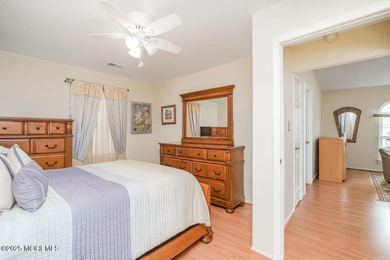 35 Ivy Ridge Close Freehold, NJ 07728 - Photo 10 of 18 a bedroom with a bed a dresser and a chandelier