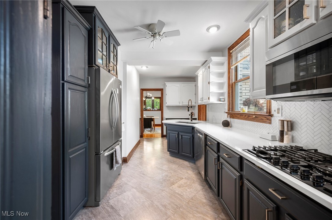 2213 Coventry Road Cleveland, OH 44118 - Photo 21 of 46 Kitchen with ceiling fan, sink, backsplash, white cabinetry, and appliances with stainless steel finishes