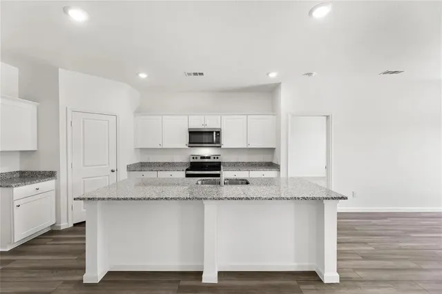 a kitchen with stainless steel appliances granite countertop a stove a sink and white cabinets
