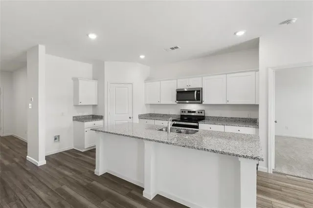 a kitchen with stainless steel appliances granite countertop a stove a sink and white cabinets