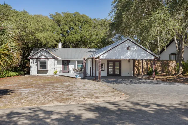 a front view of a house with a dirt yard and a large tree