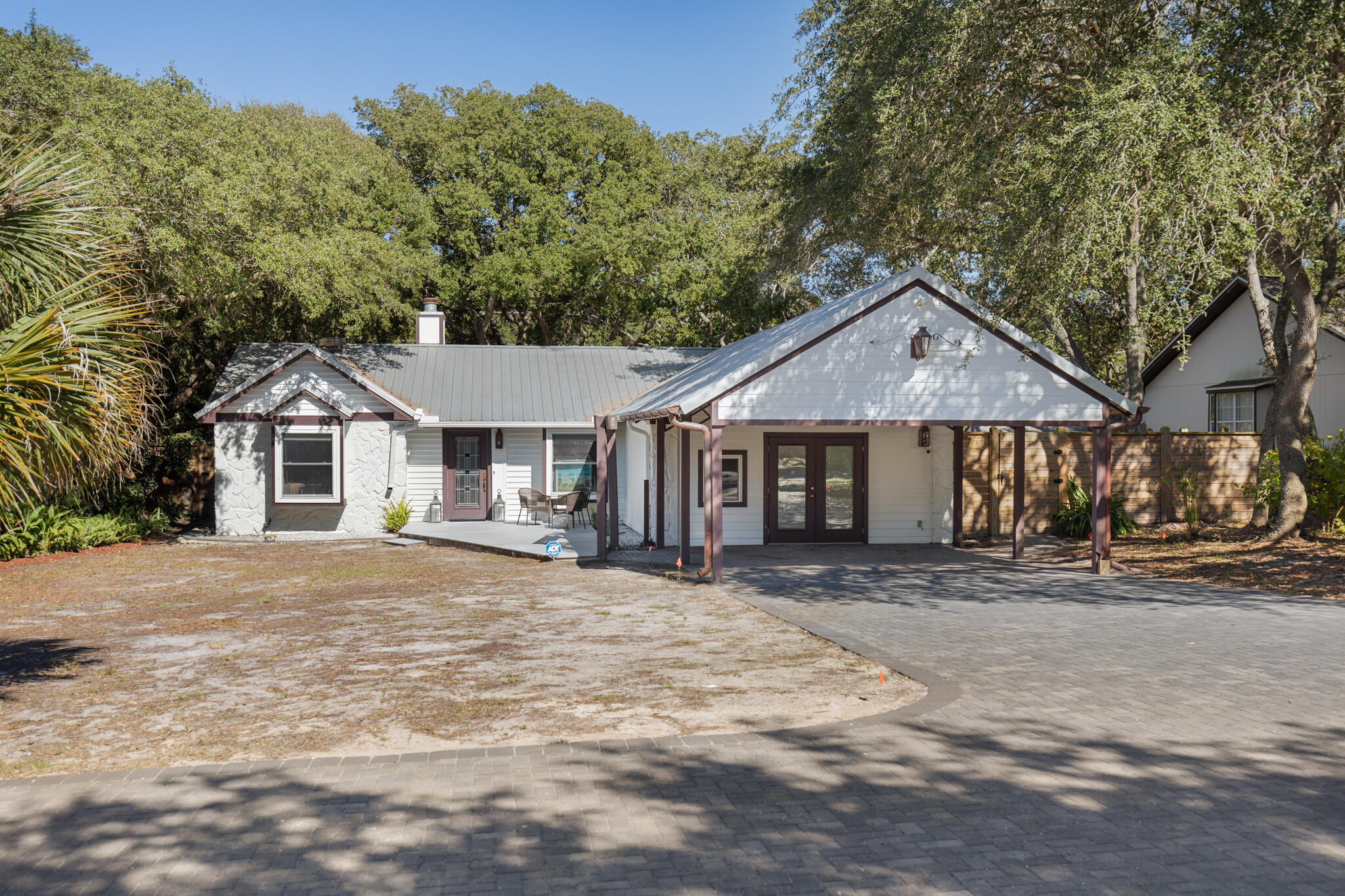 a front view of a house with a dirt yard and a large tree