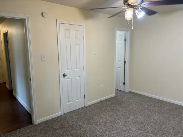 an empty room with closet and a chandelier fan
