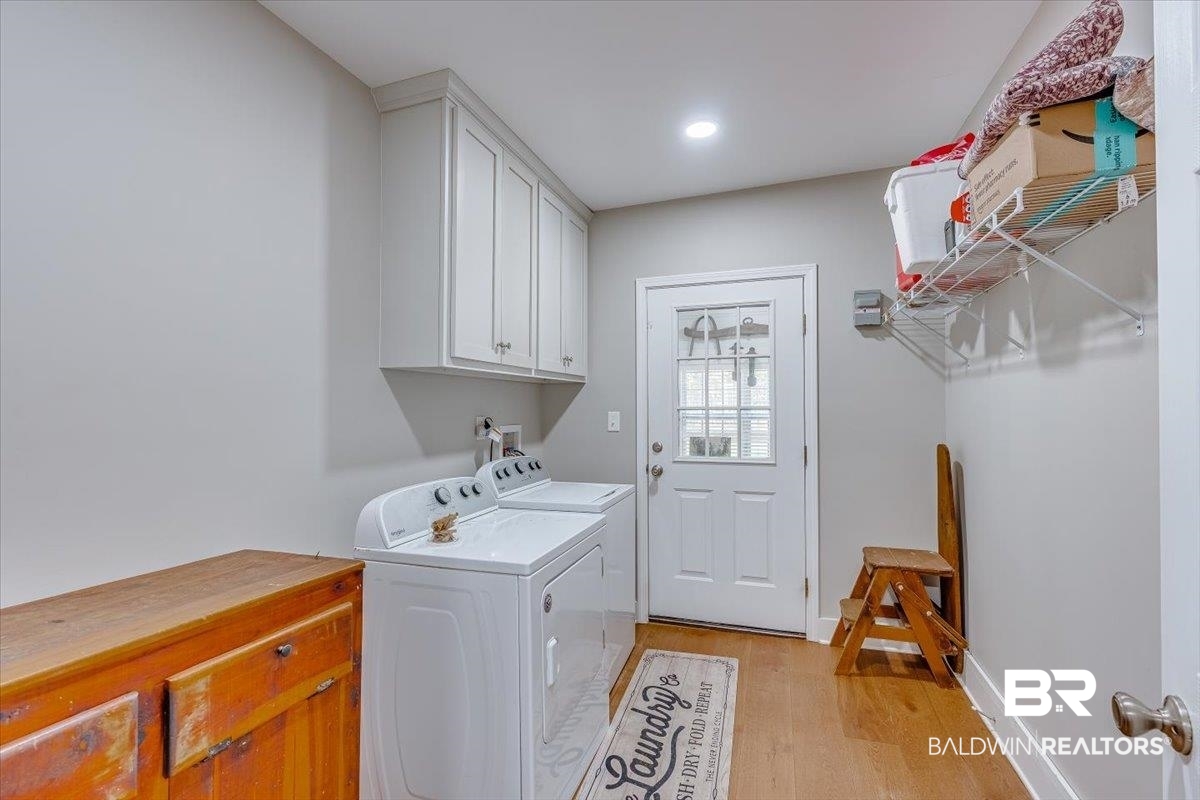 14160 Moffett Road Wilmer, AL 36587 - Photo 45 of 75 Laundry room featuring washer and clothes dryer, light wood-style floors, cabinet space, and baseboards