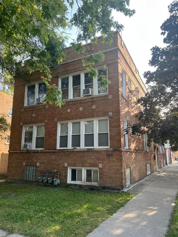 a view of a brick building next to a yard with large trees