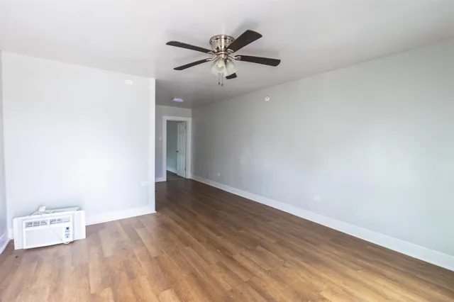 an empty room with wooden floor a ceiling fan and a window