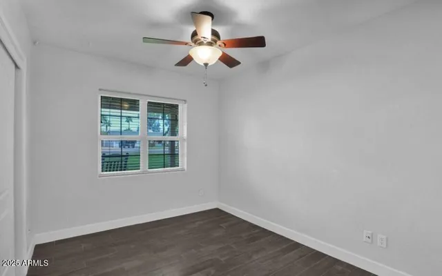 an empty room with wooden floor fan and windows
