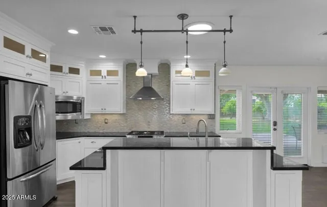 a kitchen with stainless steel appliances granite countertop a sink a refrigerator and a granite counter tops