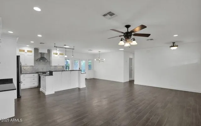 a view of an empty room with kitchen and ceiling fan