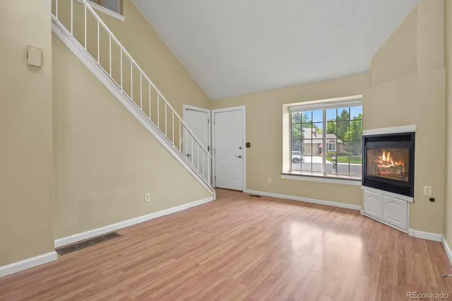 a view of an empty room with wooden floor fireplace and a window