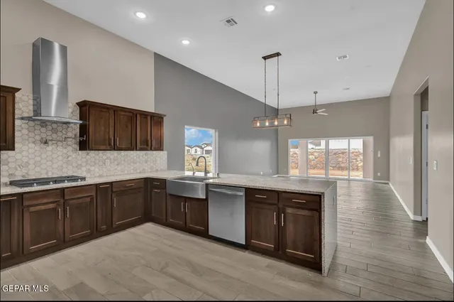 a large kitchen with granite countertop a sink and dishwasher a stove top oven with wooden floor