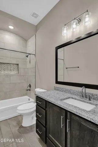 a bathroom with a granite countertop sink a toilet a mirror and bathtub