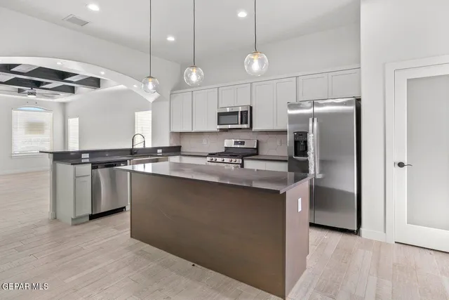 a kitchen with stainless steel appliances granite countertop a refrigerator a sink dishwasher a stove and a refrigerator with wooden floor