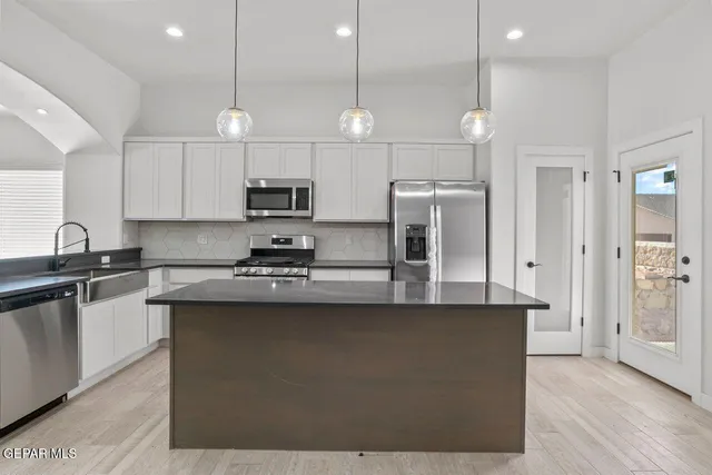 a large kitchen with stainless steel appliances kitchen island a large counter top and wooden cabinets