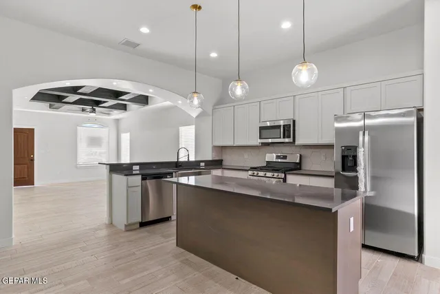 a kitchen with stainless steel appliances granite countertop a sink a stove and a refrigerator