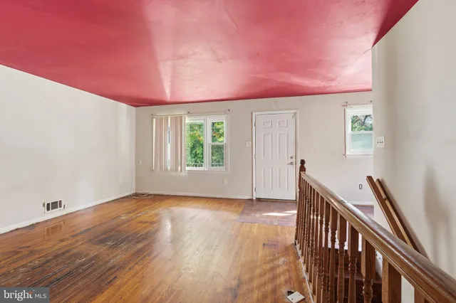 a view of an empty room with window and wooden floor