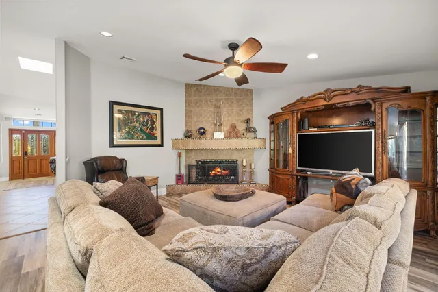 a view of a dining room and livingroom with furniture wooden floor a rug a painting and a chandelier