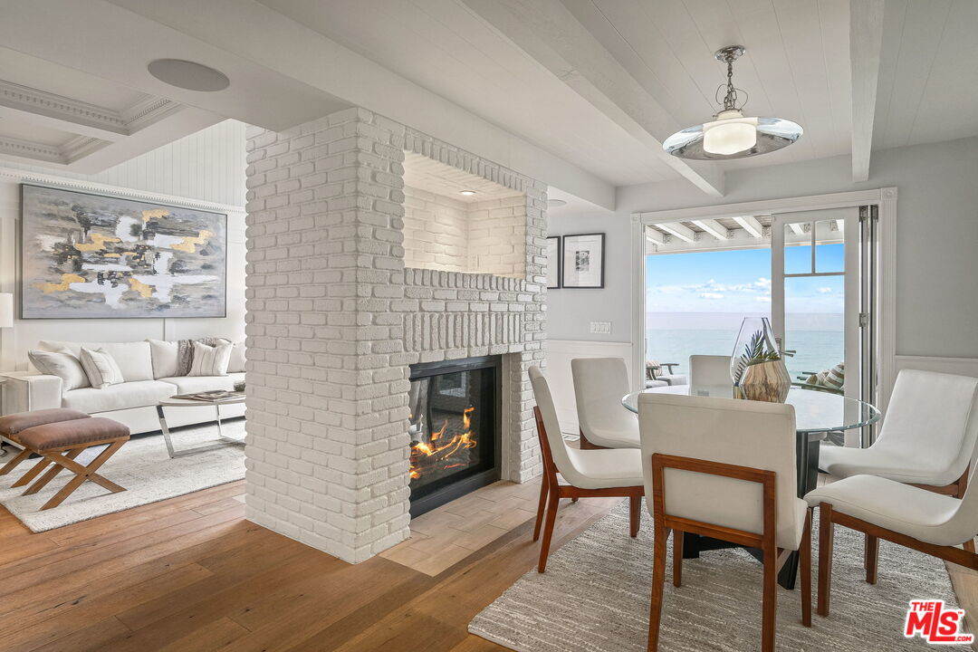 19236 Pacific Coast Highway Malibu, CA 90265 - Photo 16 of 41 a dining room with furniture a fireplace and wooden floor