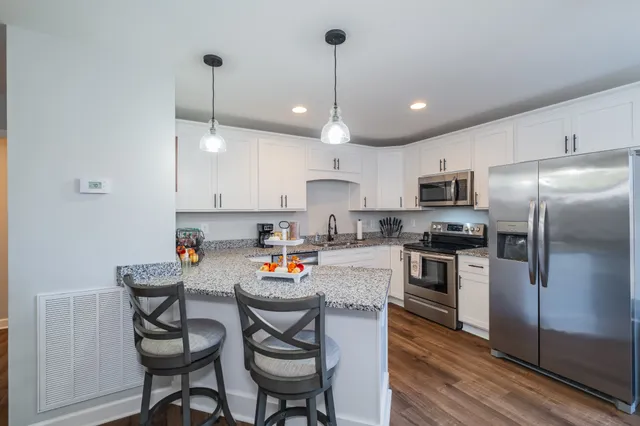 a kitchen with stainless steel appliances granite countertop a sink a stove a dining table and chairs