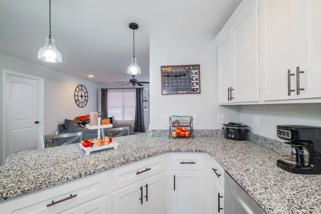 a kitchen with a sink dishwasher and white cabinets with wooden floor