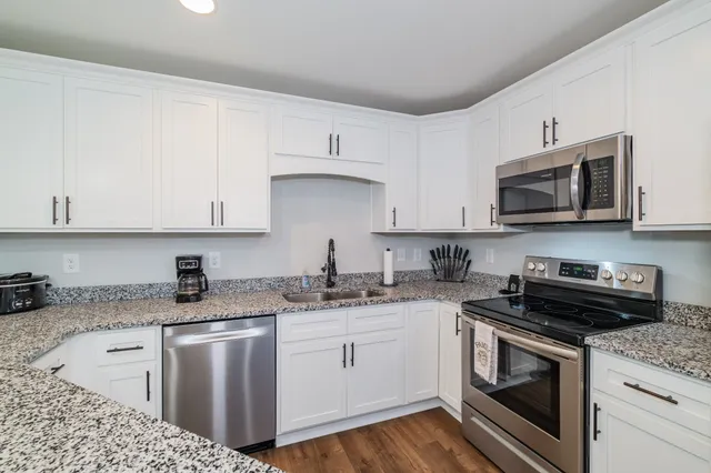 a kitchen with granite countertop white cabinets sink and stainless steel appliances