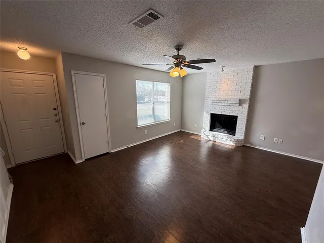 an empty room with wooden floor fireplace and windows