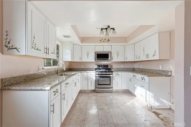 a kitchen with granite countertop white cabinets white stainless steel appliances and a sink