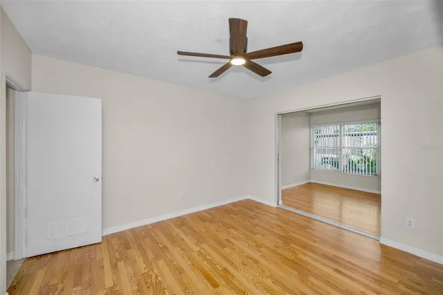 a view of empty room with wooden floor and fan