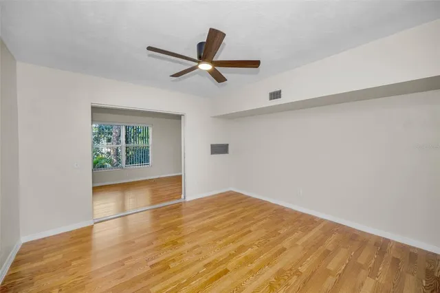 a view of an empty room with wooden floor and a window