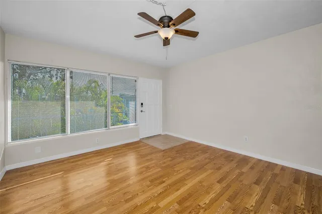 a view of a livingroom with a ceiling fan wooden floor and a ceiling fan