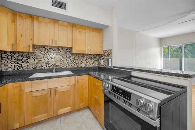a kitchen with granite countertop a sink a stove and cabinets