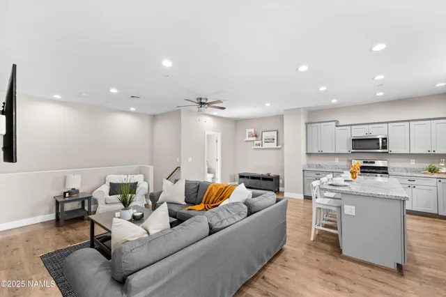 a living room with stainless steel appliances kitchen island granite countertop a couch and white cabinets