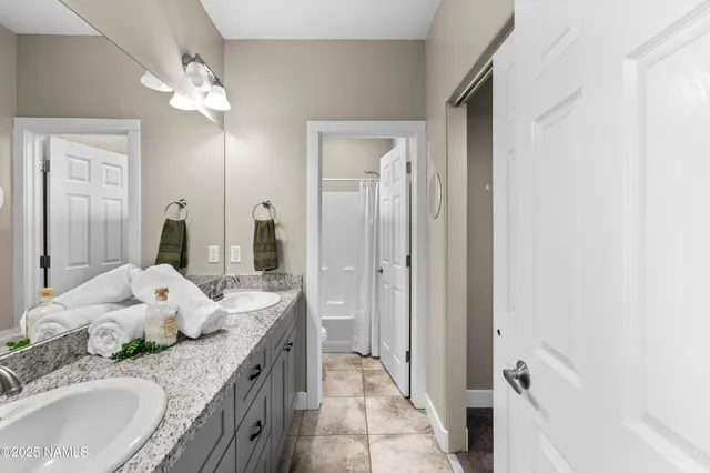 a bathroom with a granite countertop double vanity sink and mirror