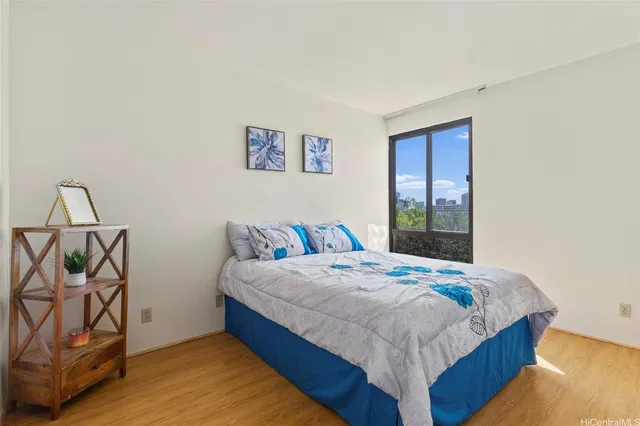 a bedroom with a bed and dresser with wooden floor