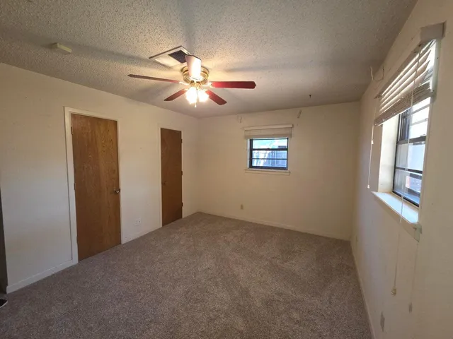 an empty room with a window and a fan