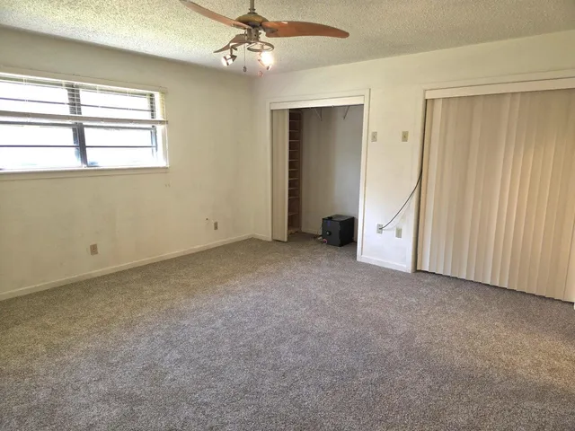 an empty room with a ceiling fan and a window