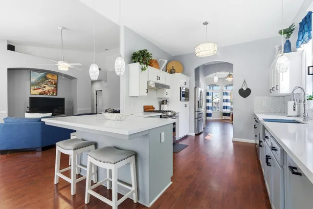 an open kitchen with wooden floor and stainless steel appliances