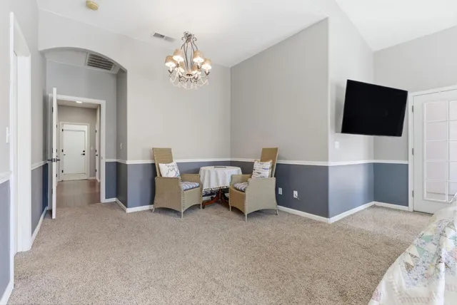 a spacious bedroom with a bed and a flat tv screen on dresser