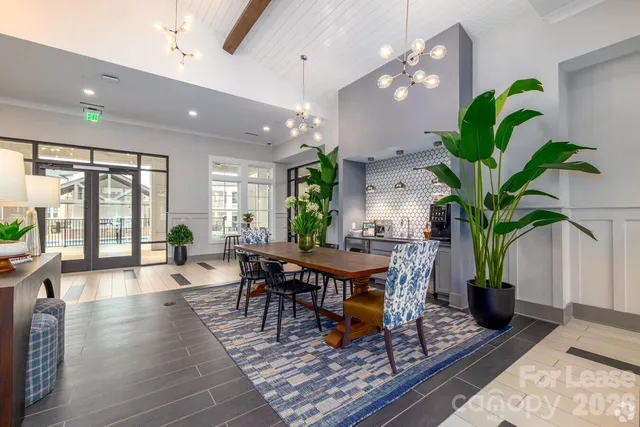 a living room filled with furniture a potted plant and a large window