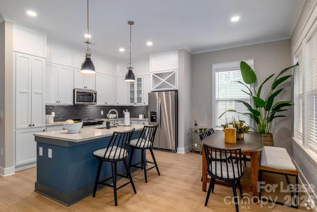 a dining room with stainless steel appliances kitchen island granite countertop a dining table chairs and white cabinets