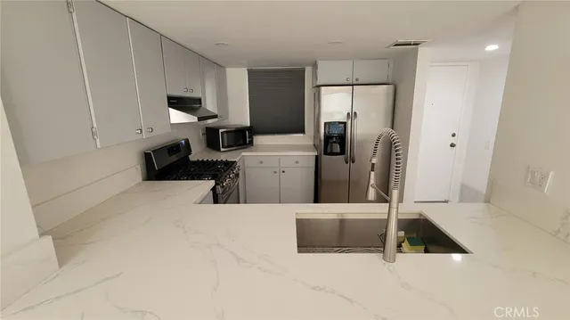 a kitchen with a refrigerator sink and white cabinets