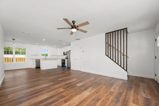 a kitchen with stainless steel appliances granite countertop a refrigerator a stove top oven a sink and dishwasher with wooden floor