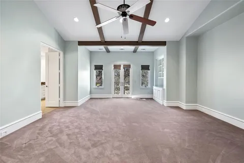 an empty room with chandelier fan and windows