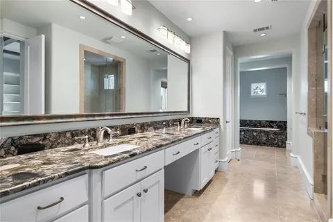 a bathroom with a granite countertop double vanity sink and a large mirror