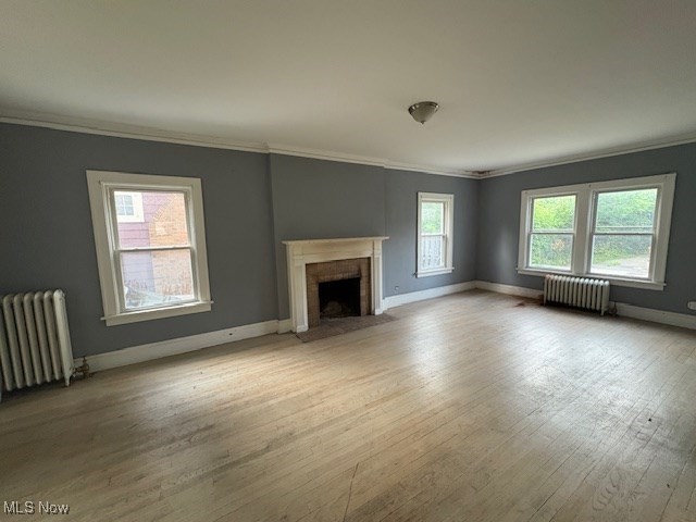 3258 Berkshire Road Cleveland, OH 44118 - Photo 8 of 23 Unfurnished living room with ornamental molding, wood finished floors, radiator, and a brick fireplace