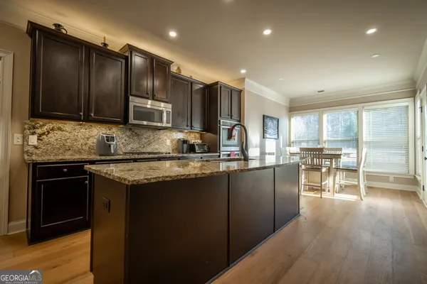 a kitchen with stainless steel appliances granite countertop wooden cabinets a refrigerator a sink a stove a microwave and wooden cabinets